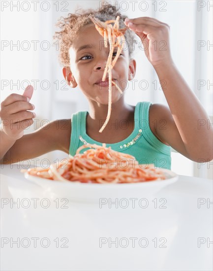 Mixed race girl eating spaghetti