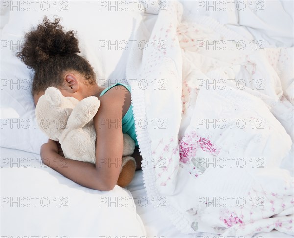 Mixed race girl sleeping with teddy bear