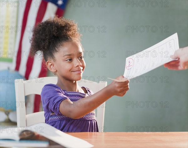 Mixed race girl receiving schoolwork from teacher