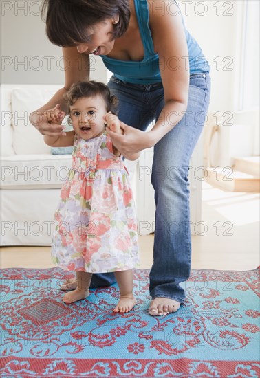 Hispanic mother helping daughter learn to walk