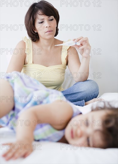 Hispanic mother taking daughter's temperature