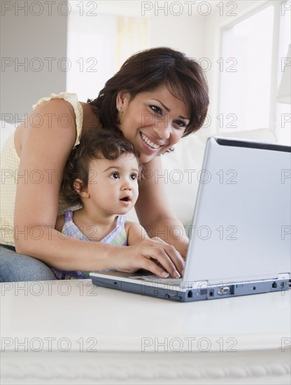 Hispanic mother and daughter looking at laptop