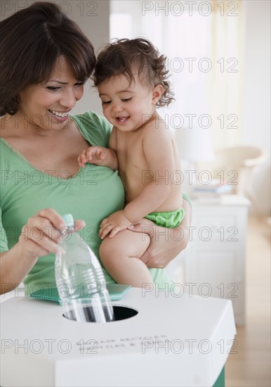 Hispanic mother teaching daughter about recycling