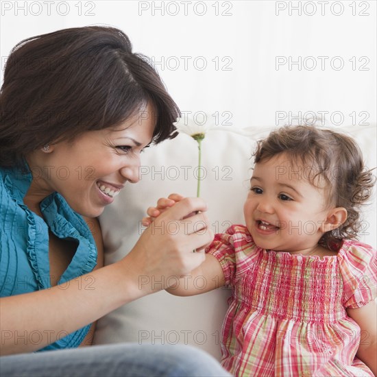 Hispanic mother handing daughter flower