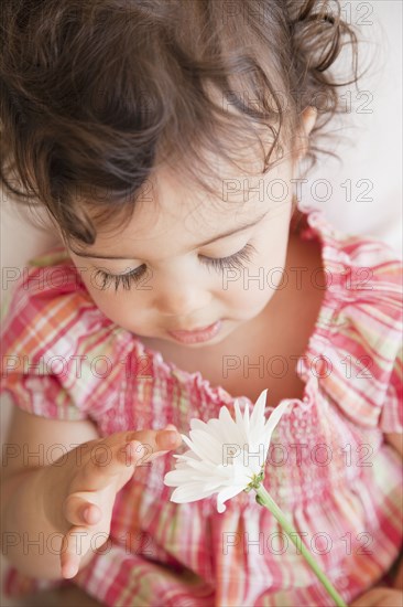 Hispanic baby girl looking at flower