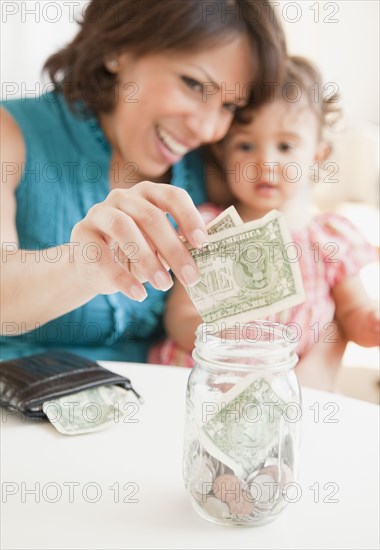 Hispanic mother and daughter saving money