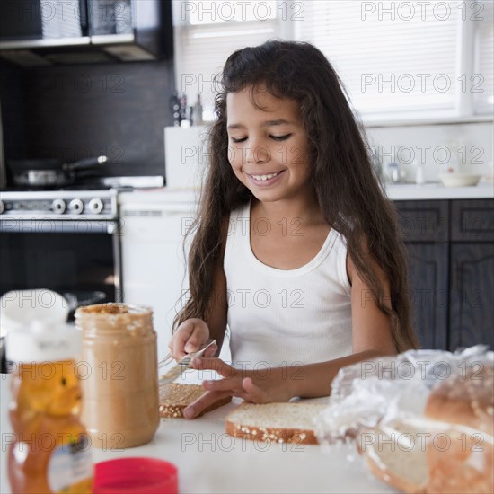 Hispanic girl making peanut butter sandwich