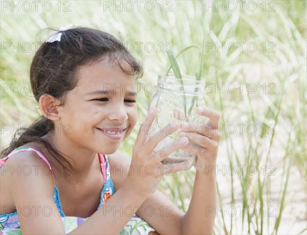 Hispanic girl looking at insect in jar