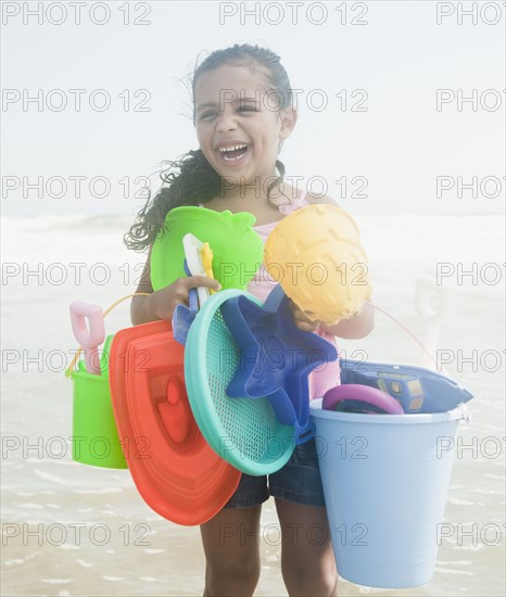 Hispanic girl holding beach toys