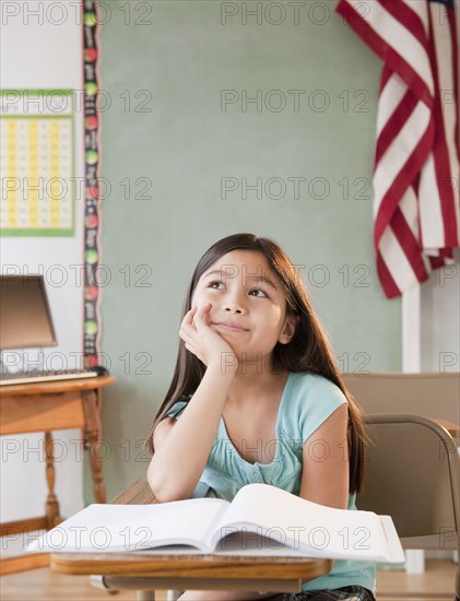 Mixed race girl daydreaming in classroom