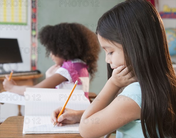 Mixed race school girl writing in notebook