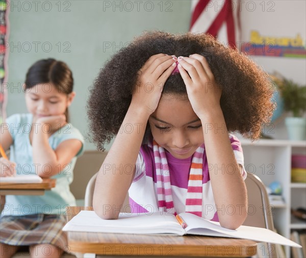 School girl reading book in classroom