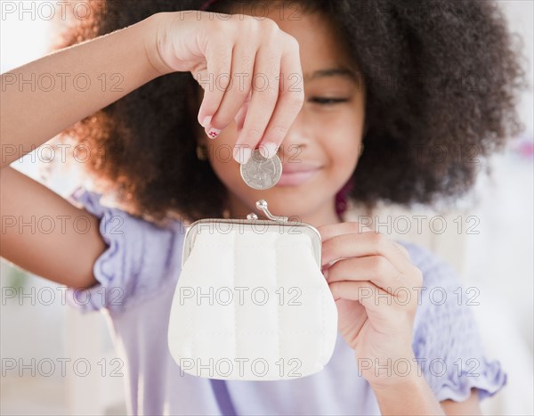 Hispanic girl putting coin into purse