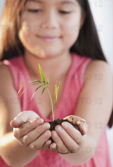 Mixed race girl holding seedling