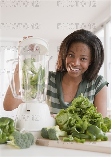 Mixed race woman blending vegetables