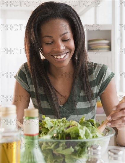 Mixed race woman tossing salad