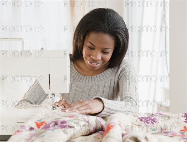 Mixed race woman sewing with sewing machine