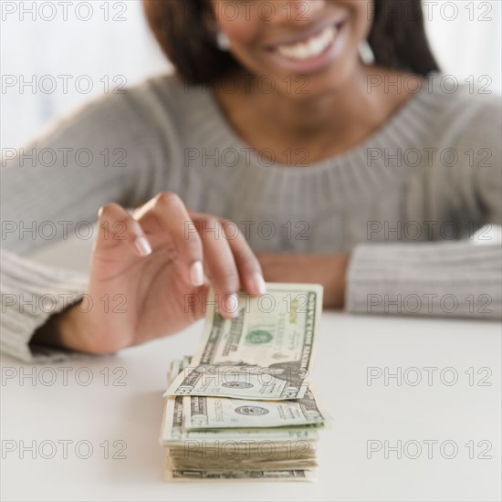 Mixed race woman taking money from stack