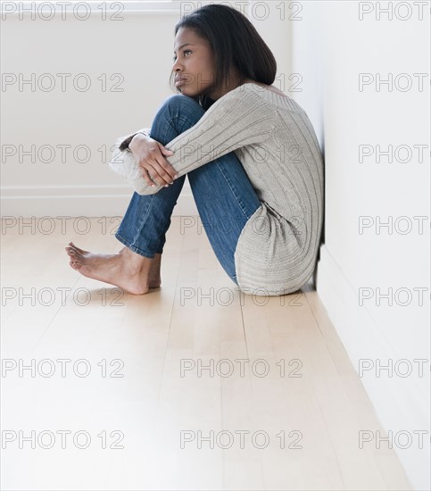 Barefoot mixed race woman sitting on floor