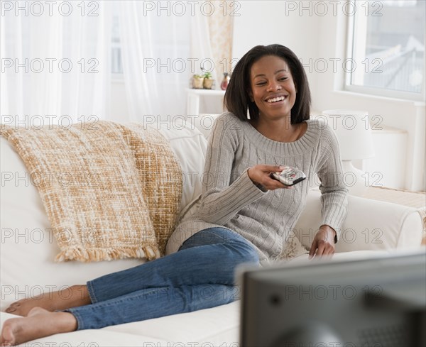 Mixed race woman watching television in living room