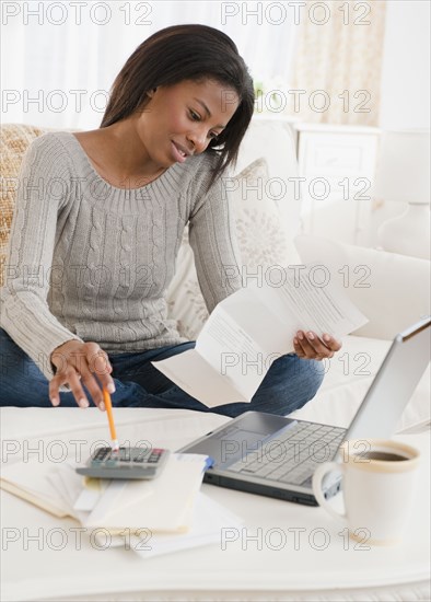 Mixed race woman paying bills in living room