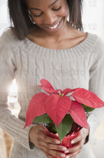 Mixed race woman holding poinsettia plant