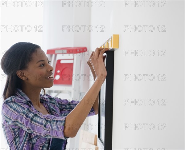 Mixed race woman hanging picture