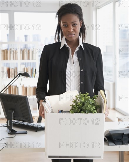 Fired mixed race businesswoman packing belongings