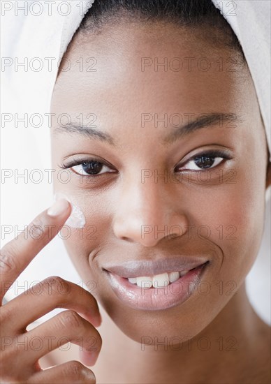 Mixed race woman using moisturizer