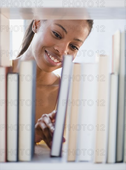 Mixed race woman taking books from shelf