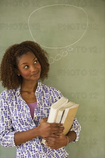 Mixed race woman standing next to thought bubble on blackboard