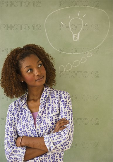 Mixed race woman standing next to thought bubble on blackboard