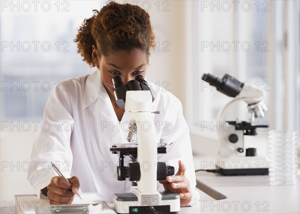 Mixed race scientist peering into microscope