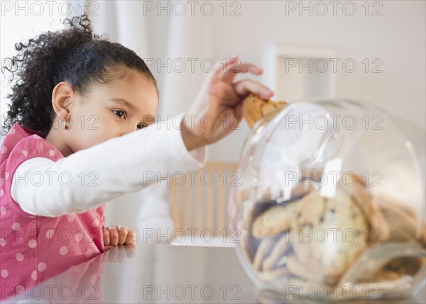 Hispanic girl taking cookie from jar