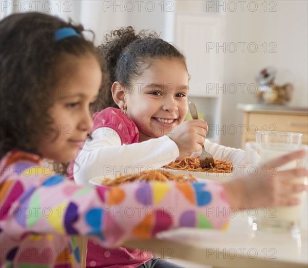 Hispanic sisters eating spaghetti