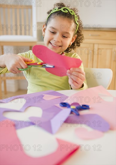 Hispanic girl cutting construction paper