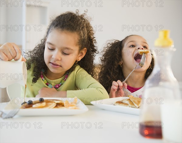 Hispanic sisters eating pancakes