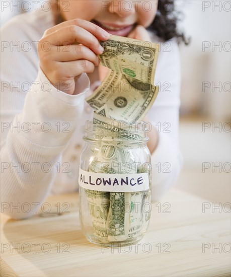 Hispanic girl putting allowance into jar