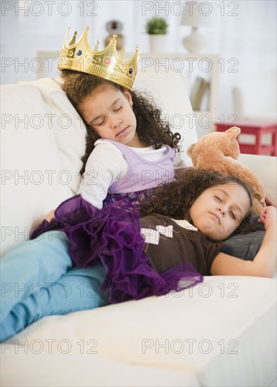 Hispanic sisters in costumes sleeping on couch