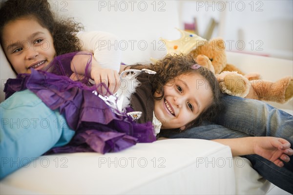 Hispanic sisters in costumes sleeping on couch