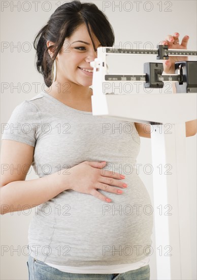 Pregnant Hispanic woman weighing herself