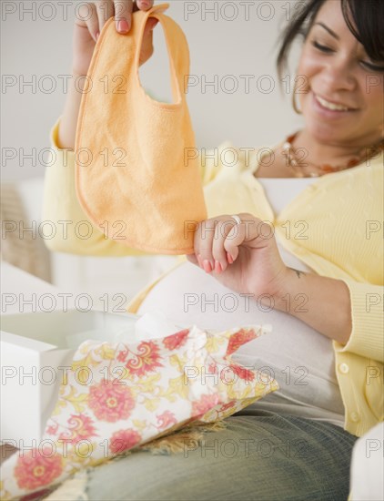 Pregnant Hispanic woman looking at baby bib