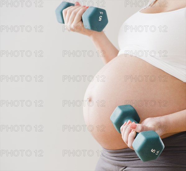 Pregnant Hispanic woman lifting dumbells