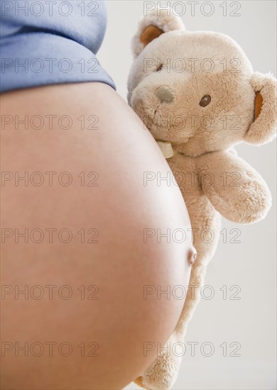 Pregnant Hispanic woman holding teddy bear