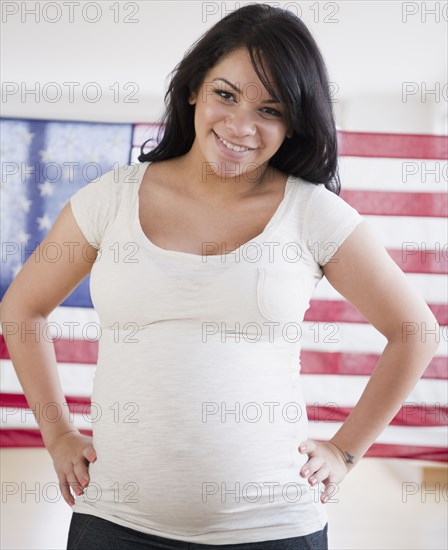 Pregnant Hispanic woman in front of American flag