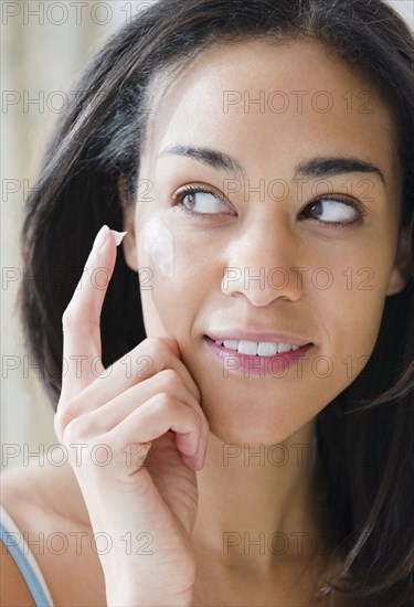 Mixed race woman applying lotion
