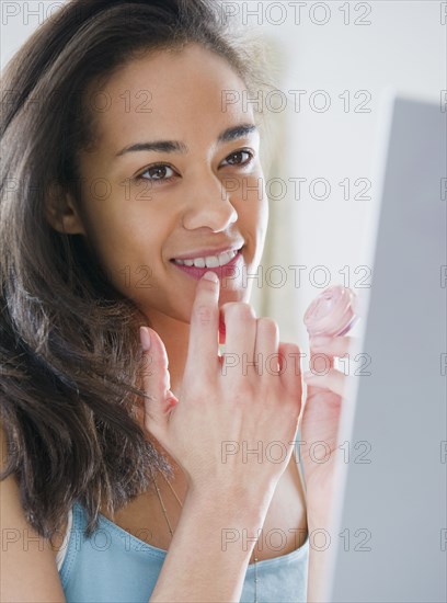 Mixed race woman applying lip gloss