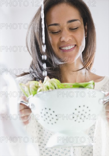 Mixed race woman rinsing spinach