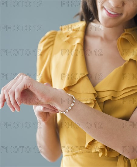 Mixed race woman putting on bracelet