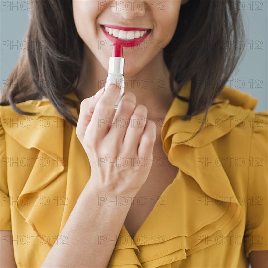 Mixed race woman applying lipstick